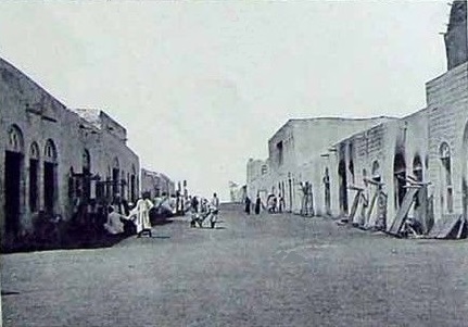 Rue commerçante de Djibouti au début du XXe siècle, avec ses arcades en pierre abritant boutiques et entrepôts.
